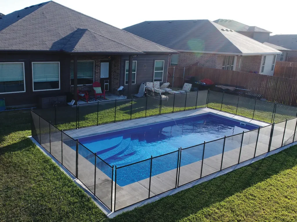 A picture of a fiberglass pool with a safety barrier around it