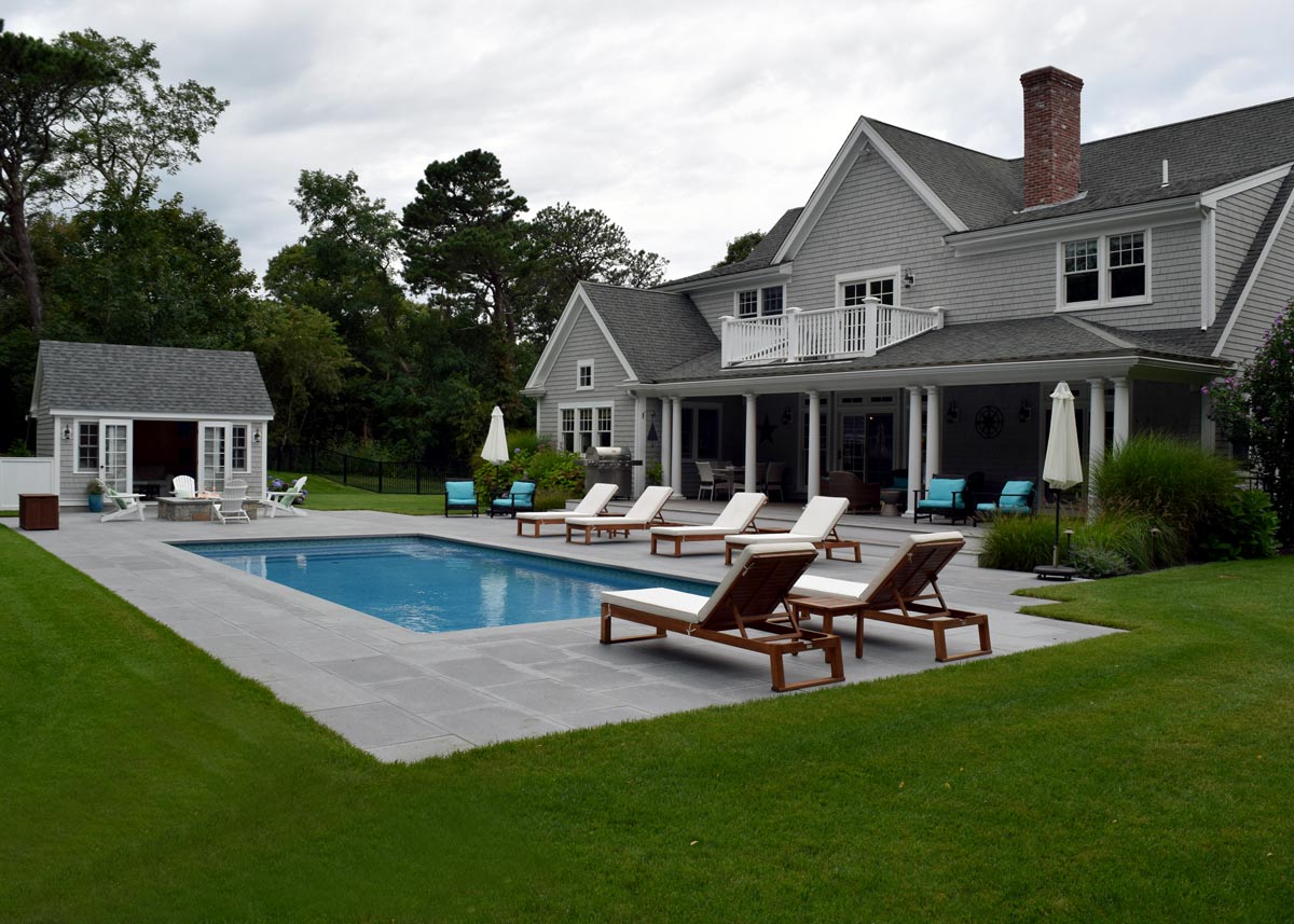 A picture of an outdoor pool with reclining pool chairs