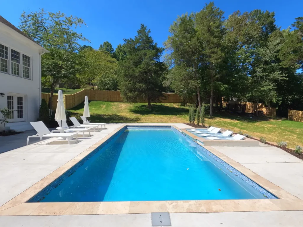 A picture of a fiberglass pool with trees in the background