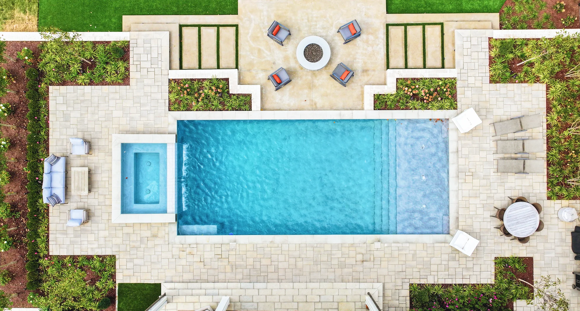 Aerial photo of a backyard swimming pool surrounded by low‑maintenance landscaping features including gravel beds and trimmed plantings, illustrating a clean poolscape.