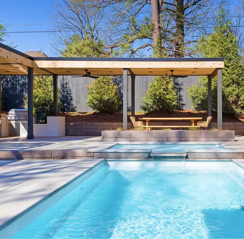 Modern backyard outdoor structure with covered patio and dining area beside a luxury pool, showcasing custom outdoor living design