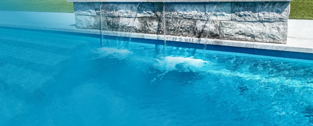 A picture of a waterfall over a fiberglass pool